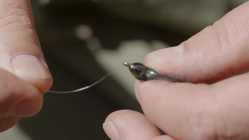 A fisherman putting a fishing lure on fishing line