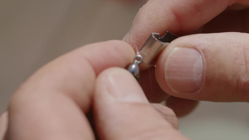 A man using clippers to cut a fishing lure from the line