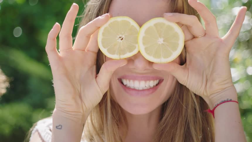 A woman holding lemons to her eyes