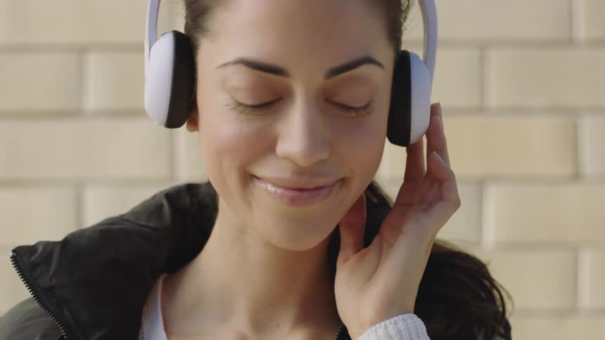 A woman shaking her head rhythmically while listening to a pair of headphones