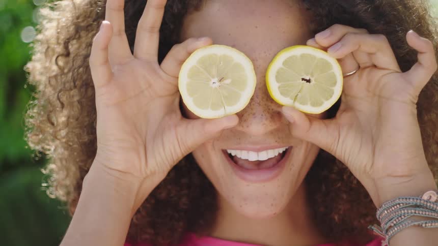 A woman holds lemons over her eyes