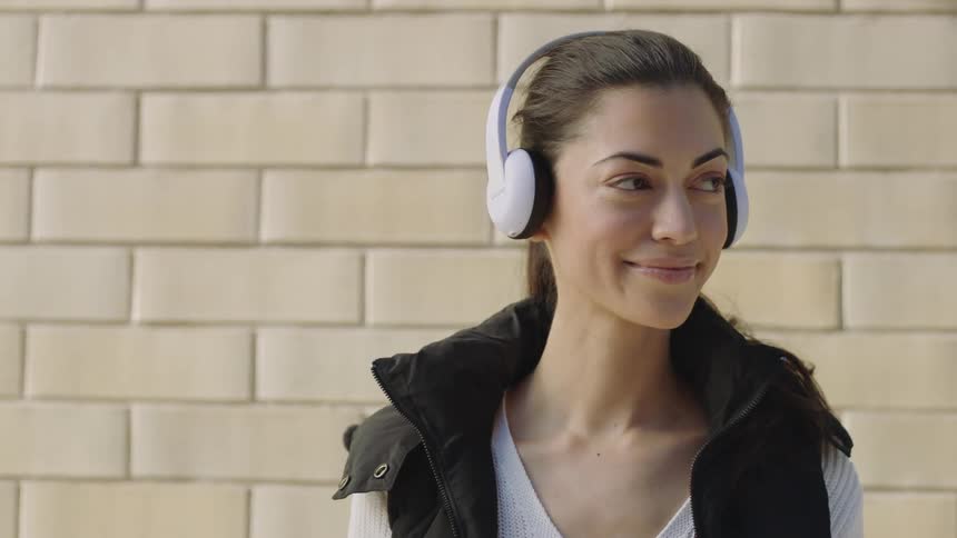 A woman puts on headphones while smiling