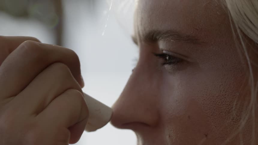 A woman applies sunscreen to her face