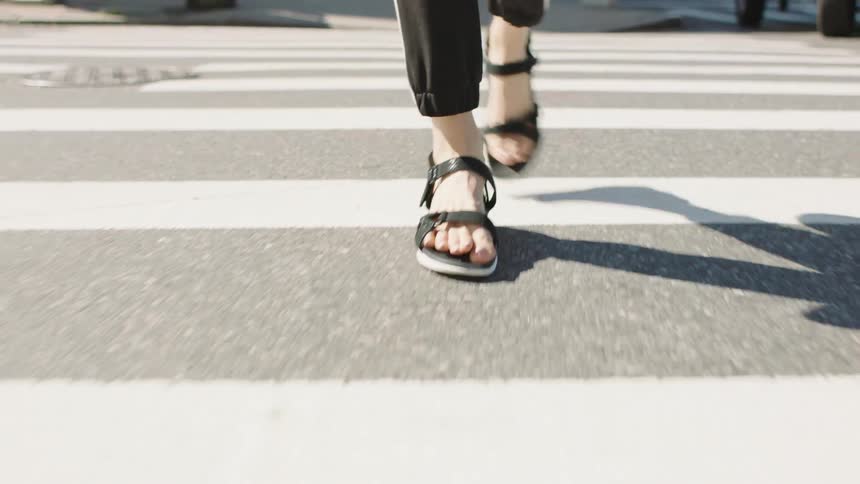 A person in sandals using a crosswalk to cross the road