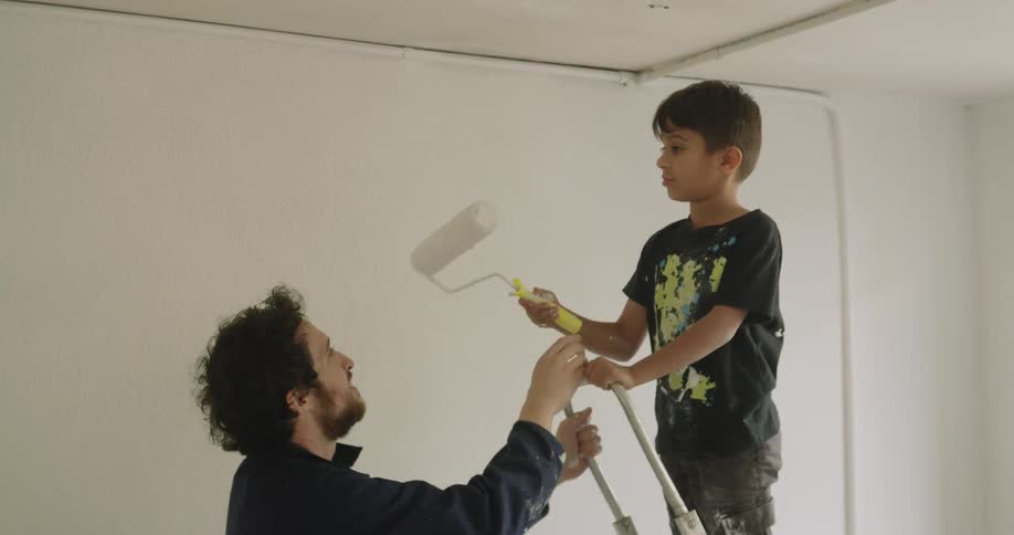 A man hands the paintbrush to the child