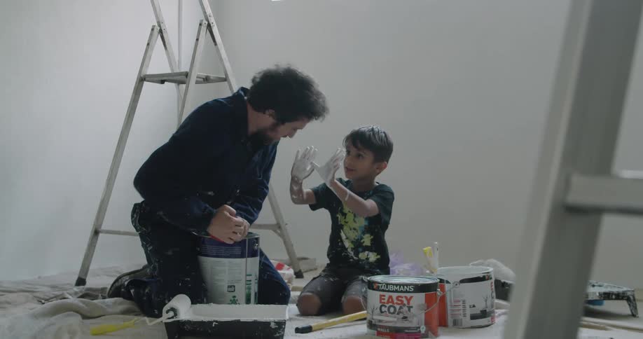A father and son get paint ready in a room together