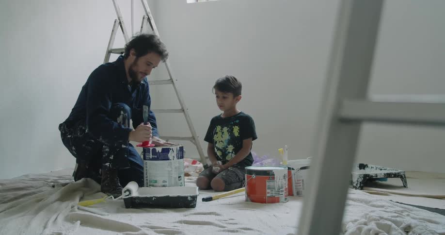 A father and son putting a lid on a paint can