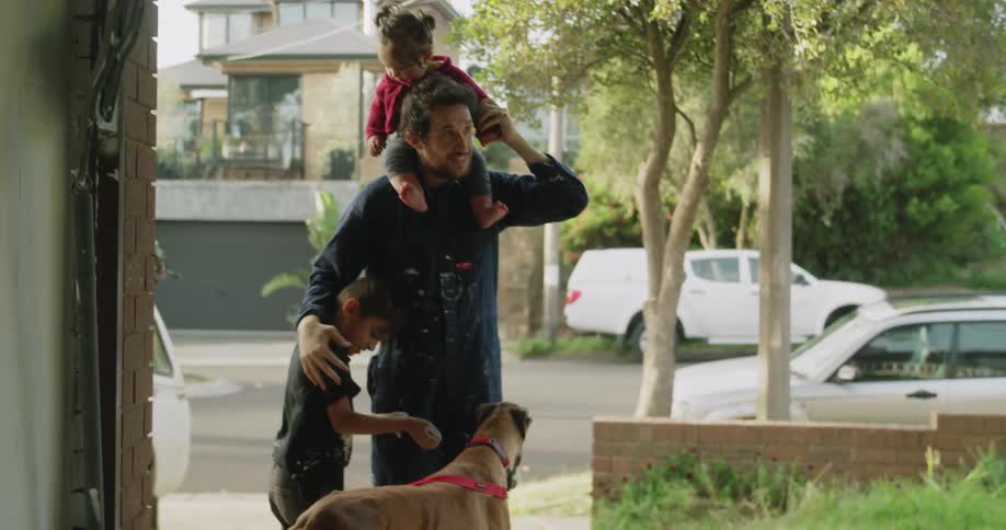 Father hugs son and carries daughter on his shoulders