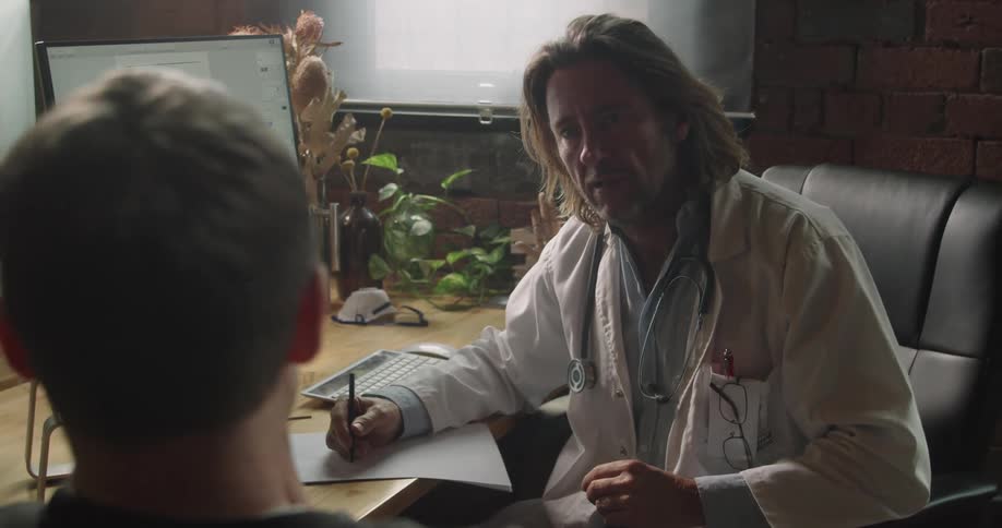 The doctor takes notes on the patient