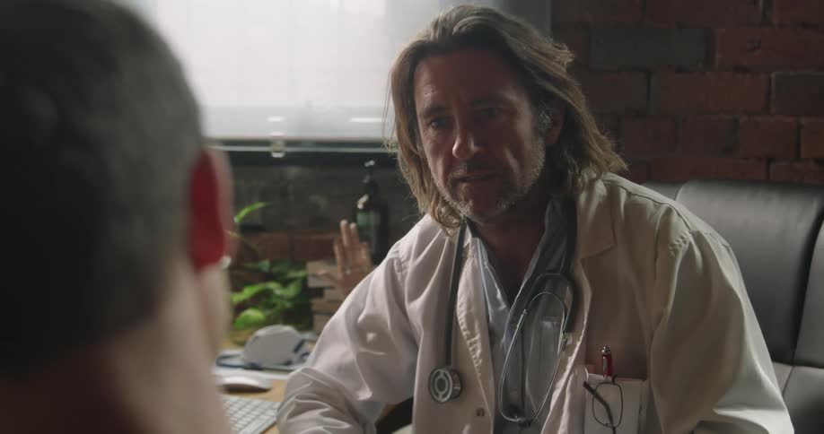 A doctor sitting at a test talking to another man