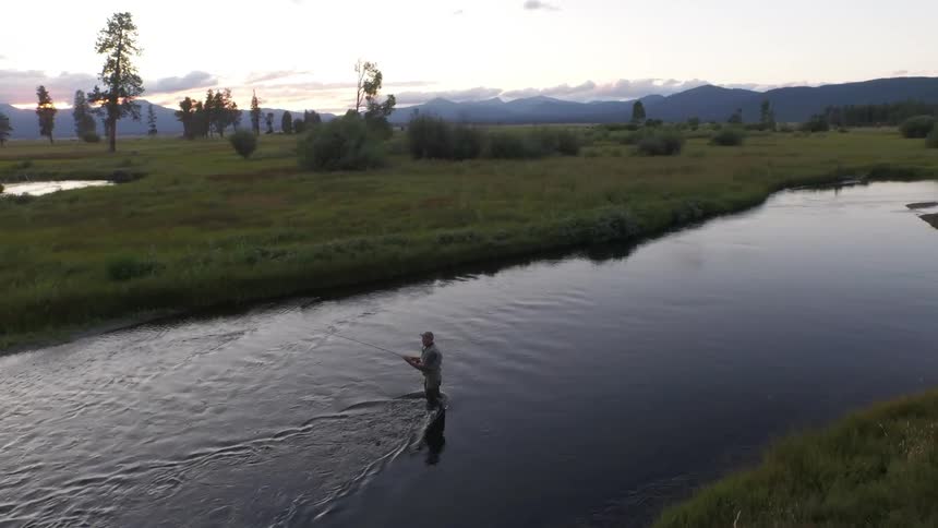 Aerial view of a man fishing in a river on a cloudy day