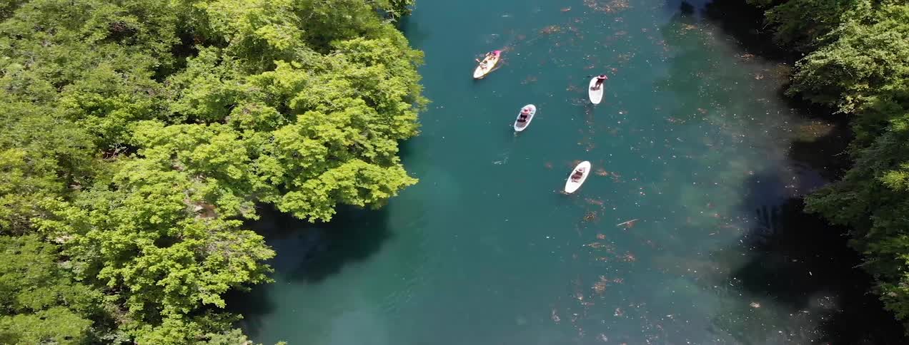 People row several boats around a river