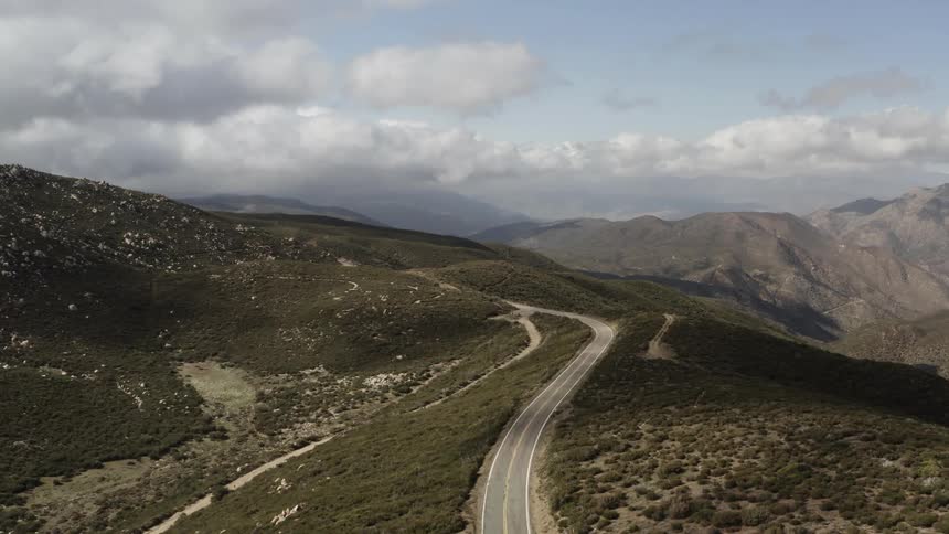 An empty mountain road along a ridge with brush on both sides