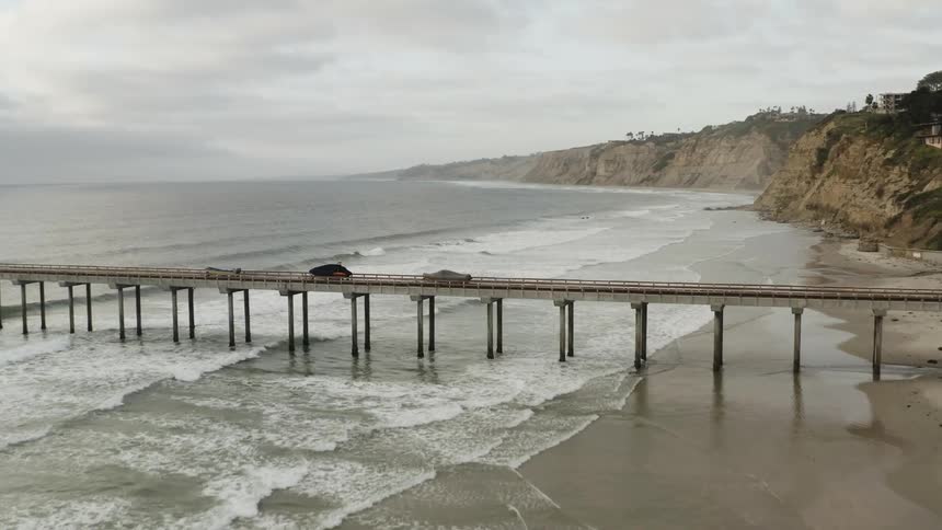 Ocean waves crash against the secluded beach on a cloudy day