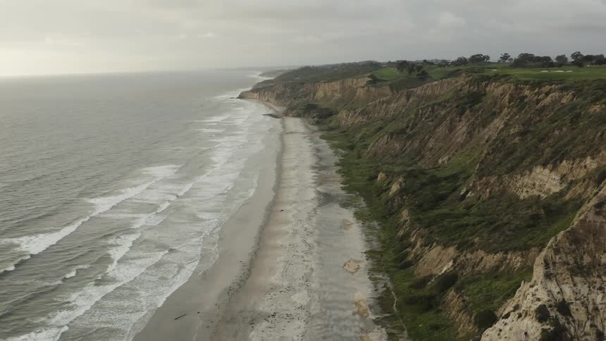 Waves roll in along a cliff lined shore