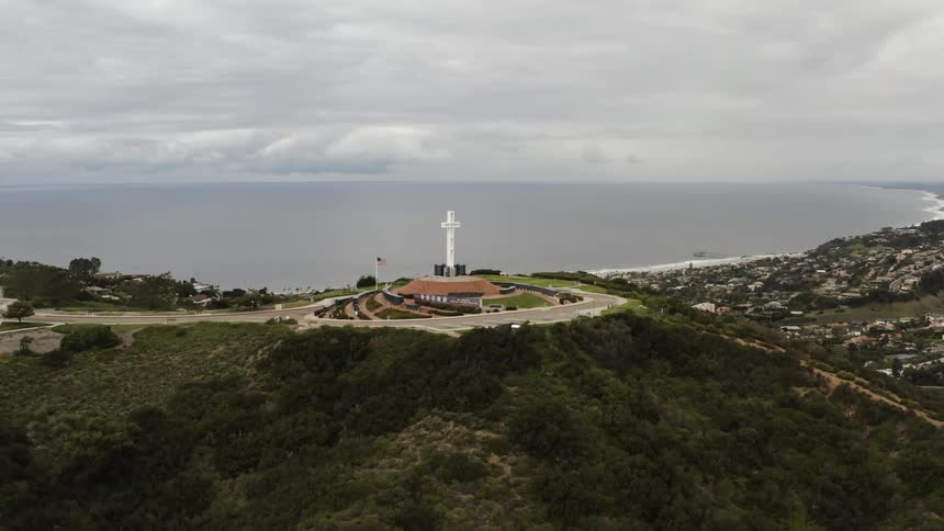 A large cross sits on the hill above the city