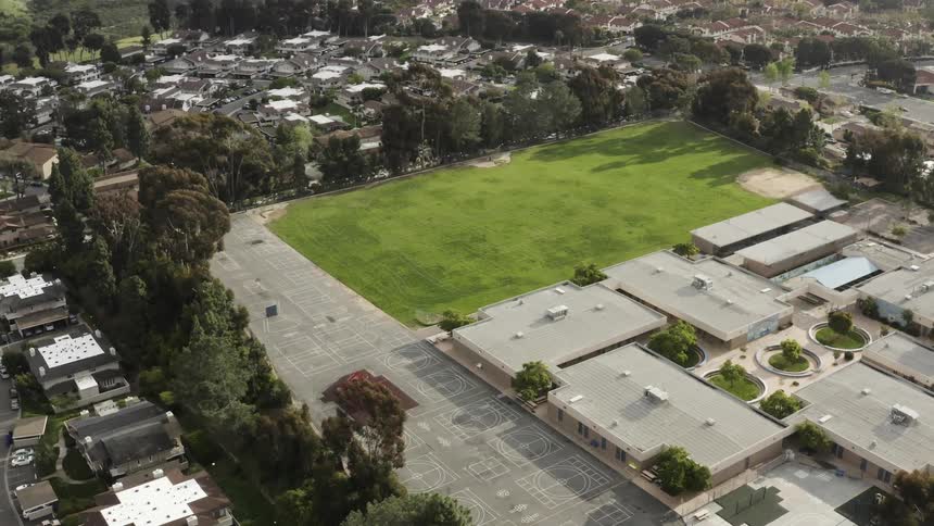 Buildings line a grassy park behind a school