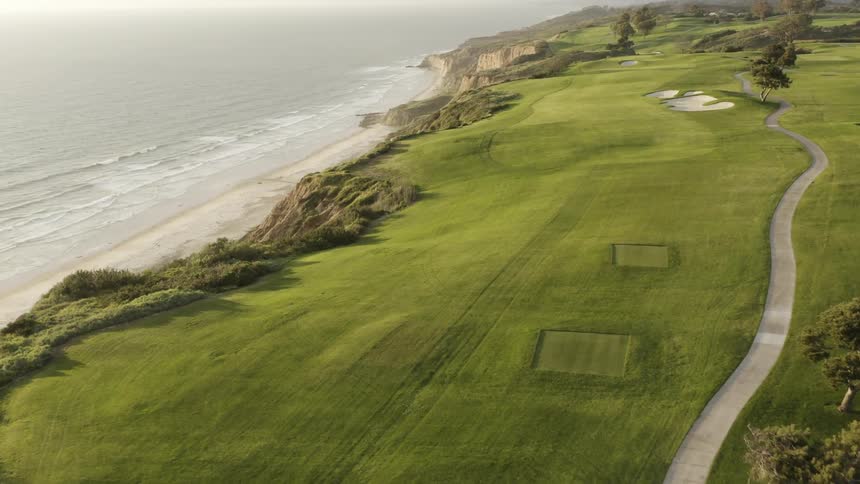 The lush green grass of an empty golf course on the cliffs above the ocean