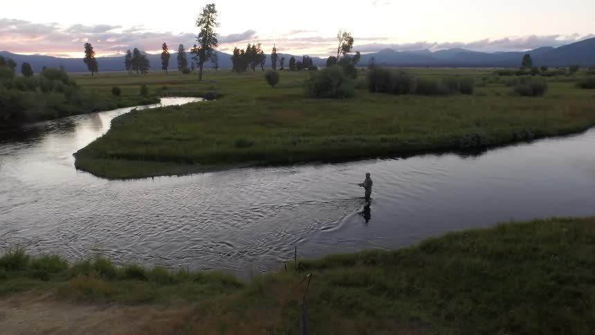 A fisherman in a stream casts his line