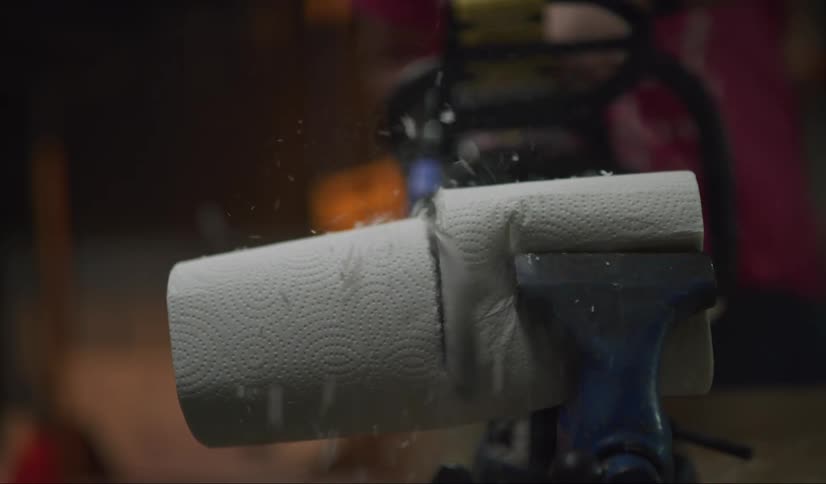 A chainsaw cuts a roll of paper towels in half for use as toilet paper.