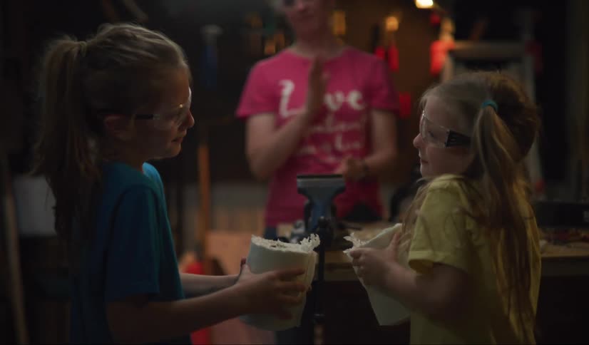 A mom hands to her children a paper towel role cut in half for toilet paper during the 2020 shortage
