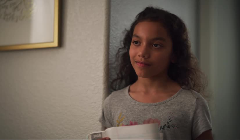 A close up of young girl as she enters a room, but stops in doorway and watches something