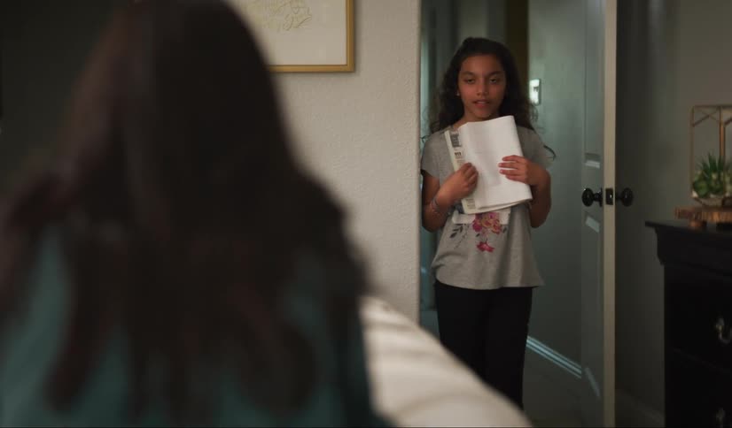 A young girl enters room, but stops in doorway and watches her mom pray.