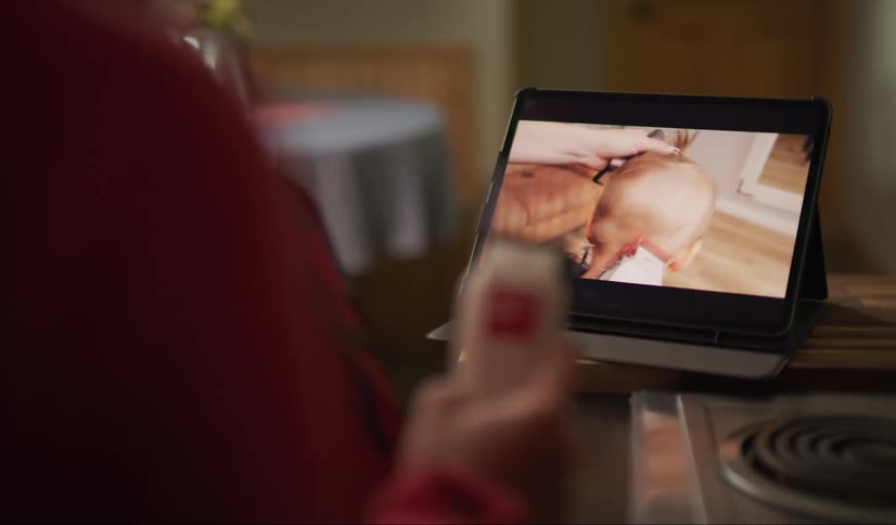 A woman watches a hair cutting tutorial on a tablet in order to learn how to cut hair