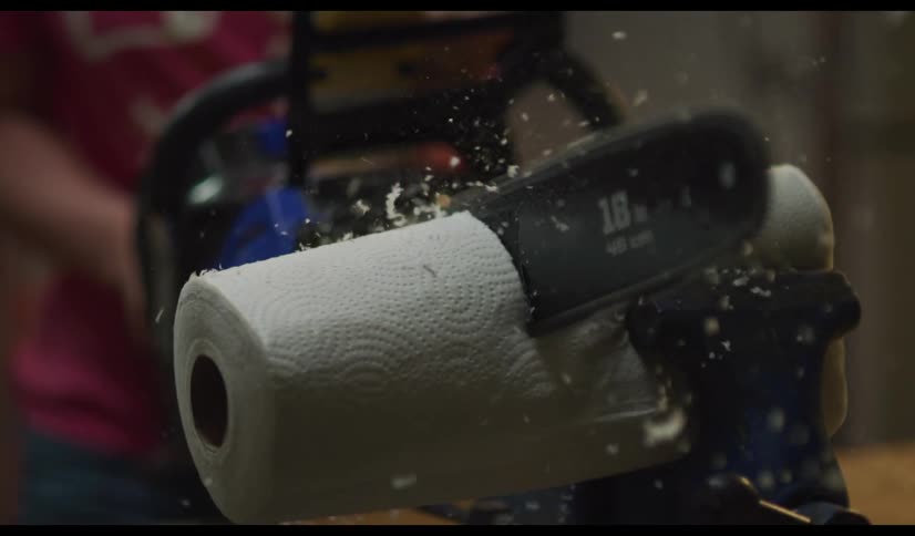Slow motion shot of a chainsaw cutting through a role of paper towels.