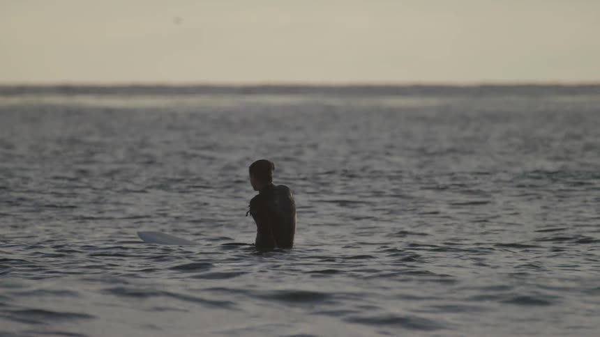 A surfer floats on a surfboard in the ocean