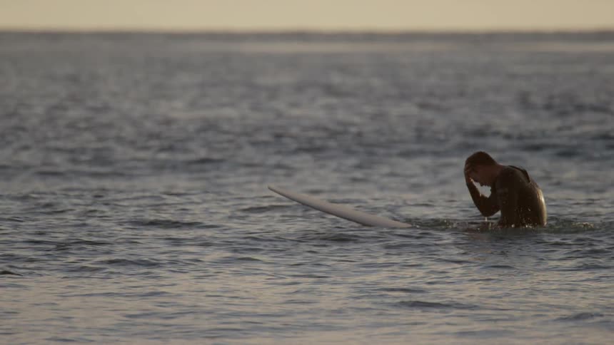 Man sits on surfboard in the water
