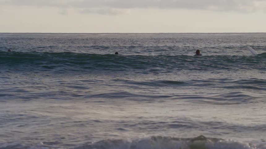 Surfers sit on their boards in the ocean