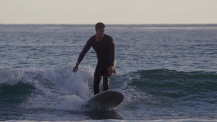 A man paddles on his surfboard in the ocean