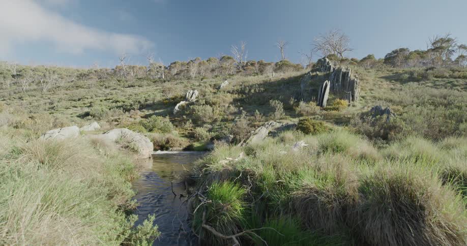 Small narrow stream and green hill landscape during the day