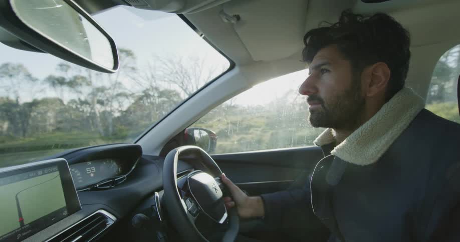 A man is driving his car past the woods