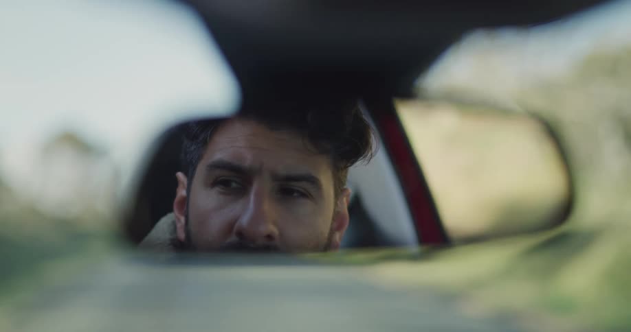 Man can be seen in rear view mirror as he drives down road