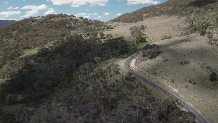 A vehicle driving down a curvy road on hills