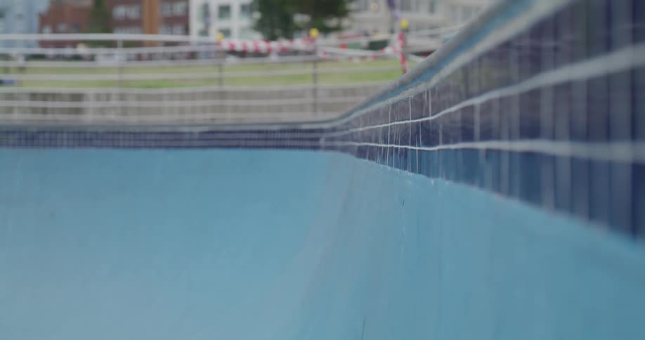 Young man rollerblades inside pool at day