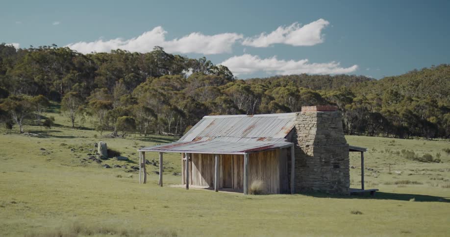 Small wood cabin in rural area on a grass field at day