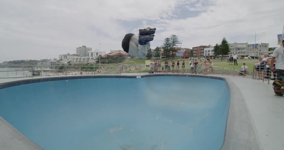 A group of people watching a man rollerblade in a pool