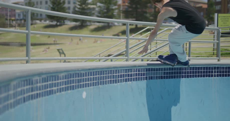 A teenage boy performs a skating trick in a public park