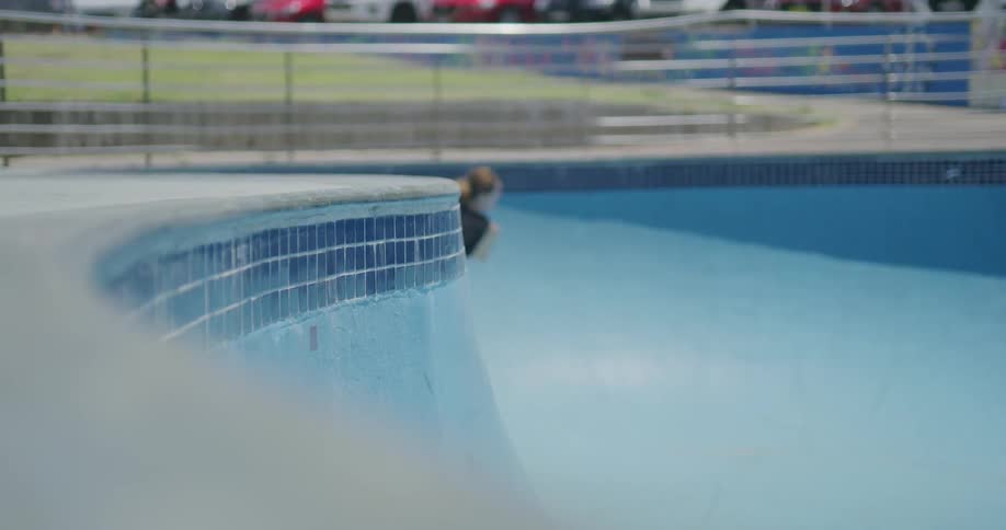 Young man in roller skates uses skate park at day