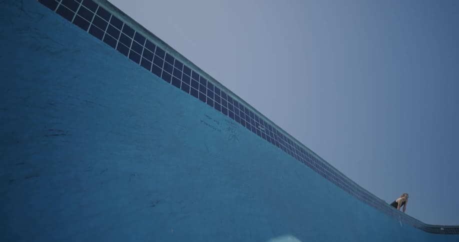 A young man looks into an empty skate pool