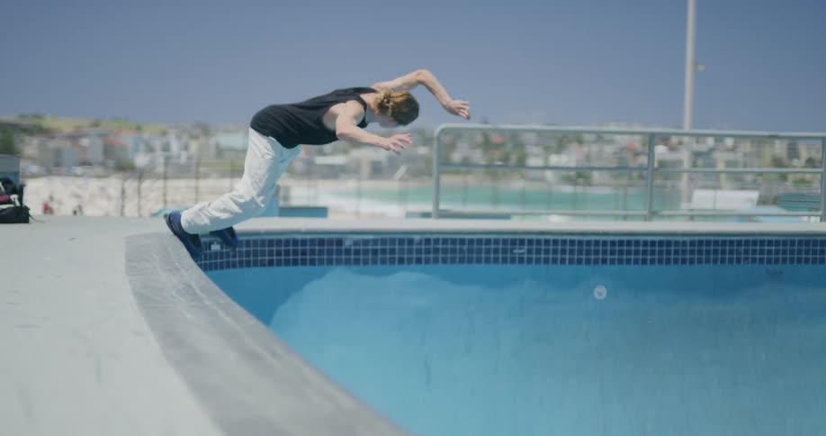 Long haired man rollerblades in the blue skate bowl