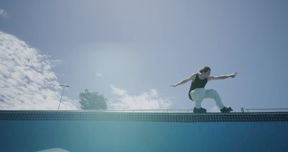 A man skates fast around the lip of the pool