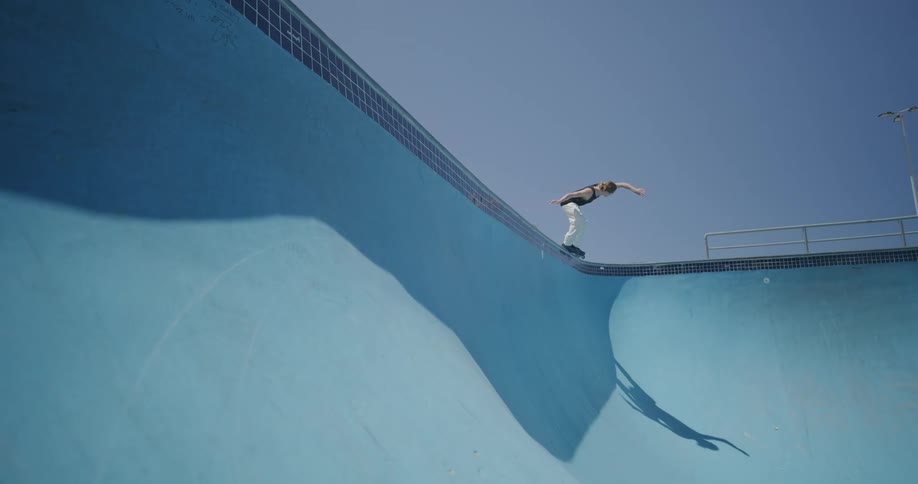 Young man roller skating on empty pool at day