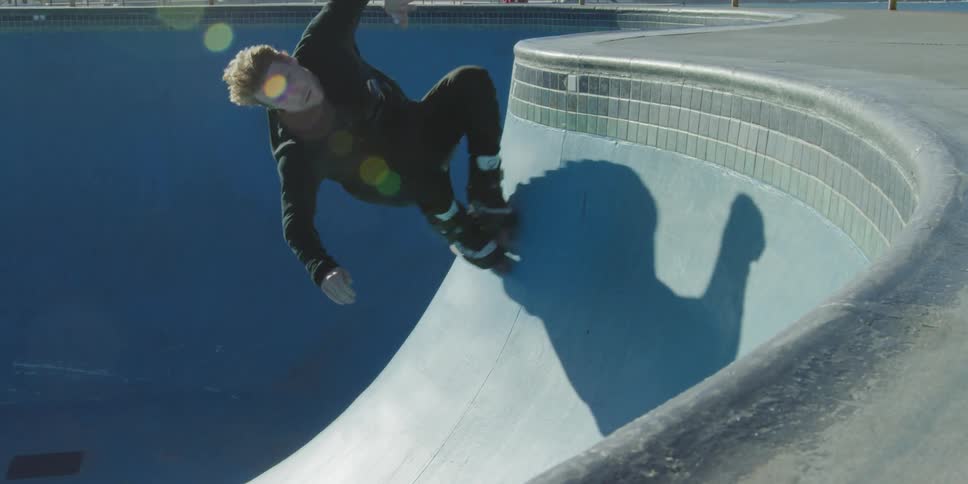 Man rollerblades in the blue skate bowl