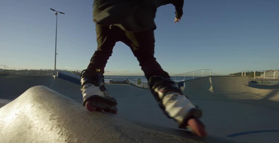 Young man rollerblading at skate park near beach at day