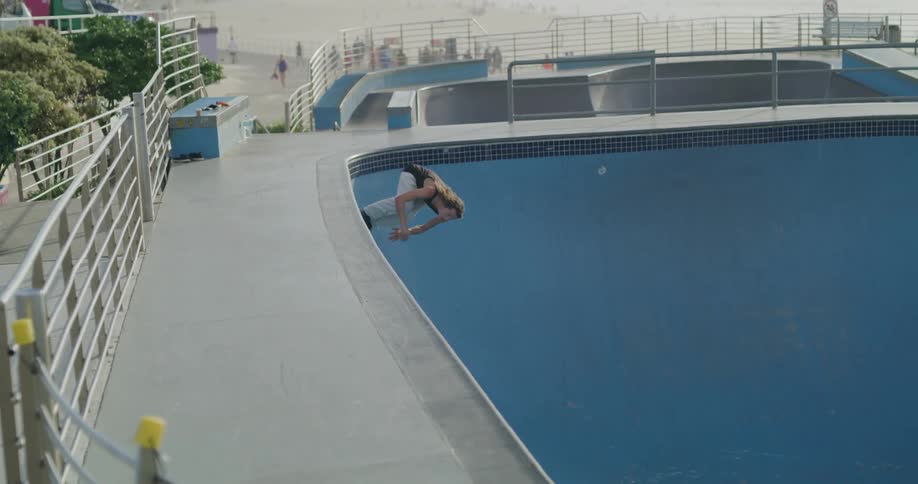 Man rollerblading inside empty pool in city near coast at day