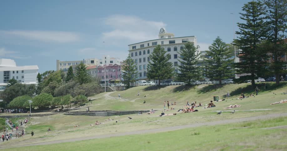 A large group of people walk and relax in a public park in a city